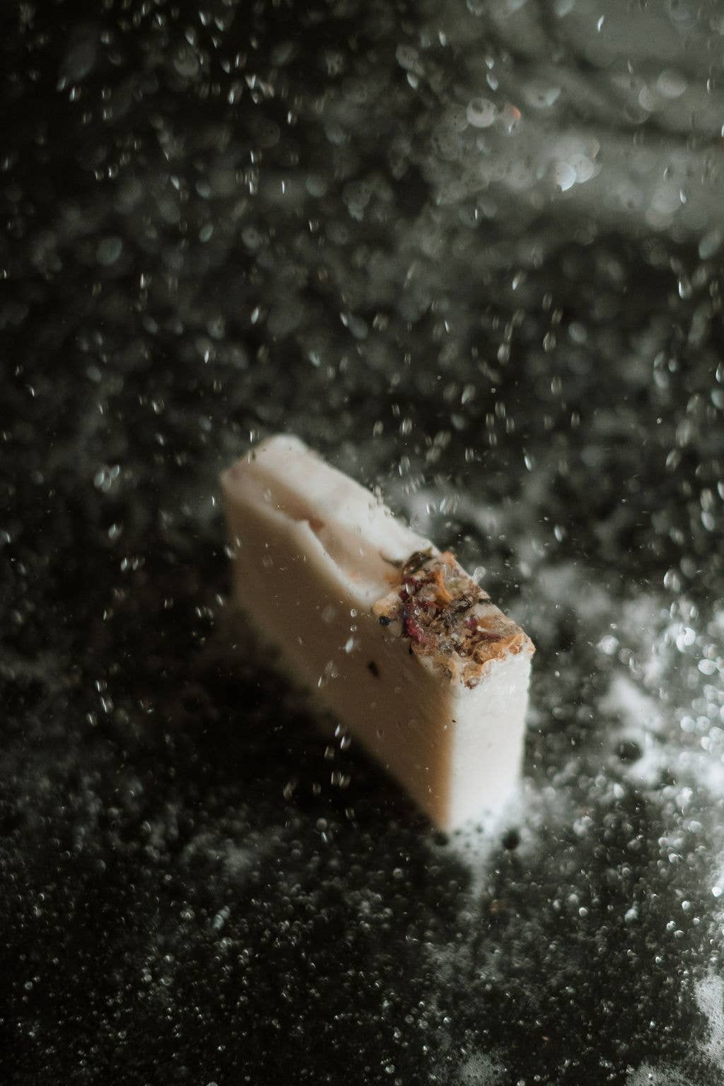 handmade soap standing on shower floor with water falling on it