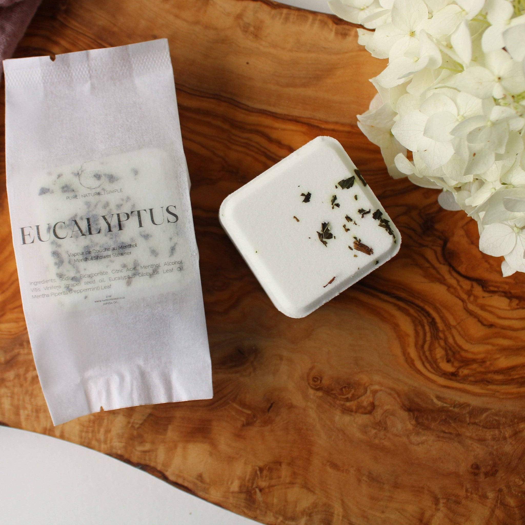 Eucalyptus shower steamer on a wooden surface with white flowers.