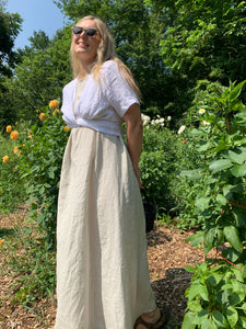 woman wears Lights of All's caroline dress and stella top in a garden