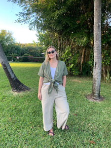 wide leg beige pants worn with white linen tank top and short sleeve green linen wrap top on top.