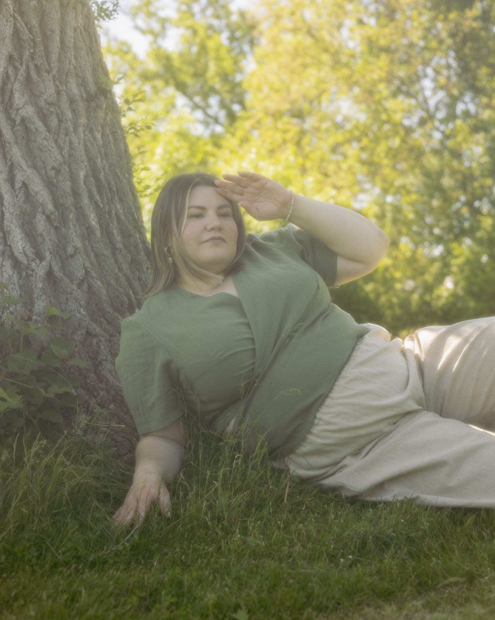 Model wears the Lights of All stella top and Freedom Pant while laying in the grass