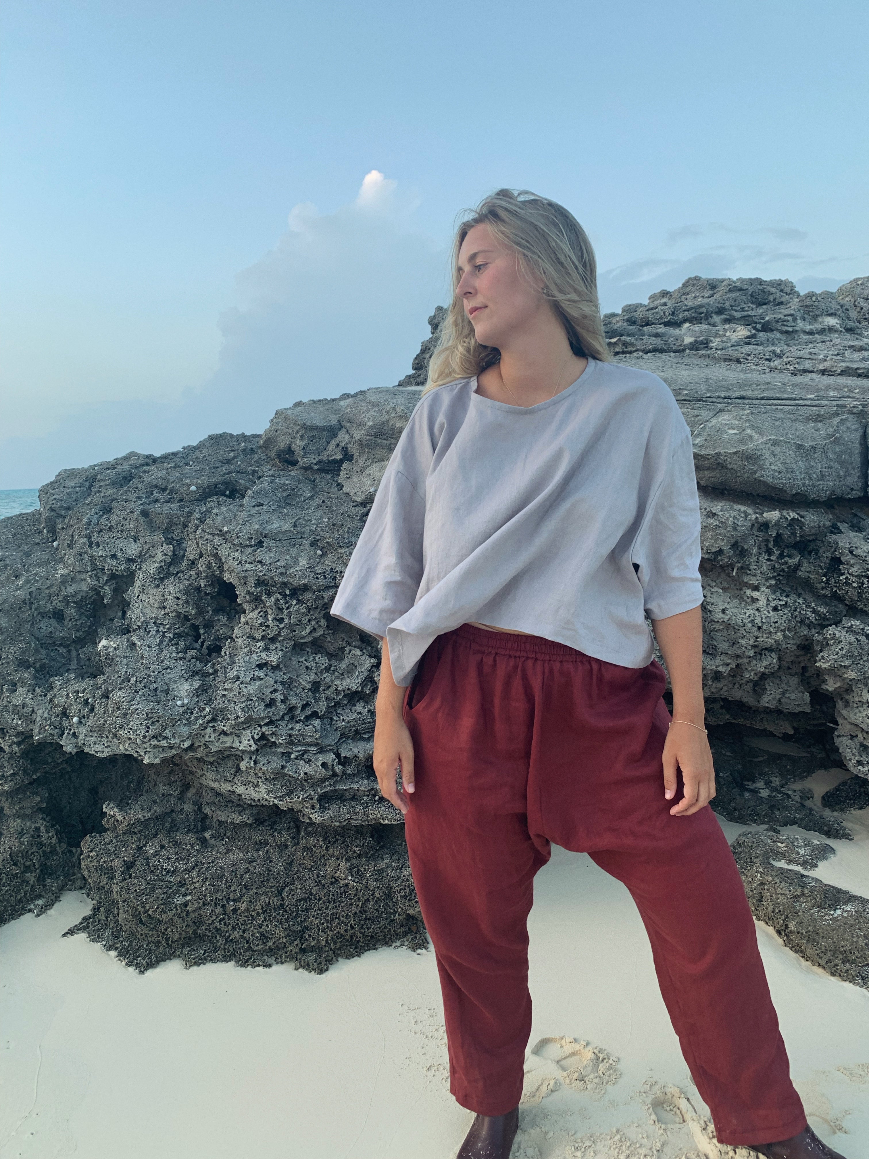 woman wears burgundy harem style pants and oversized grey t-shirt on the beach