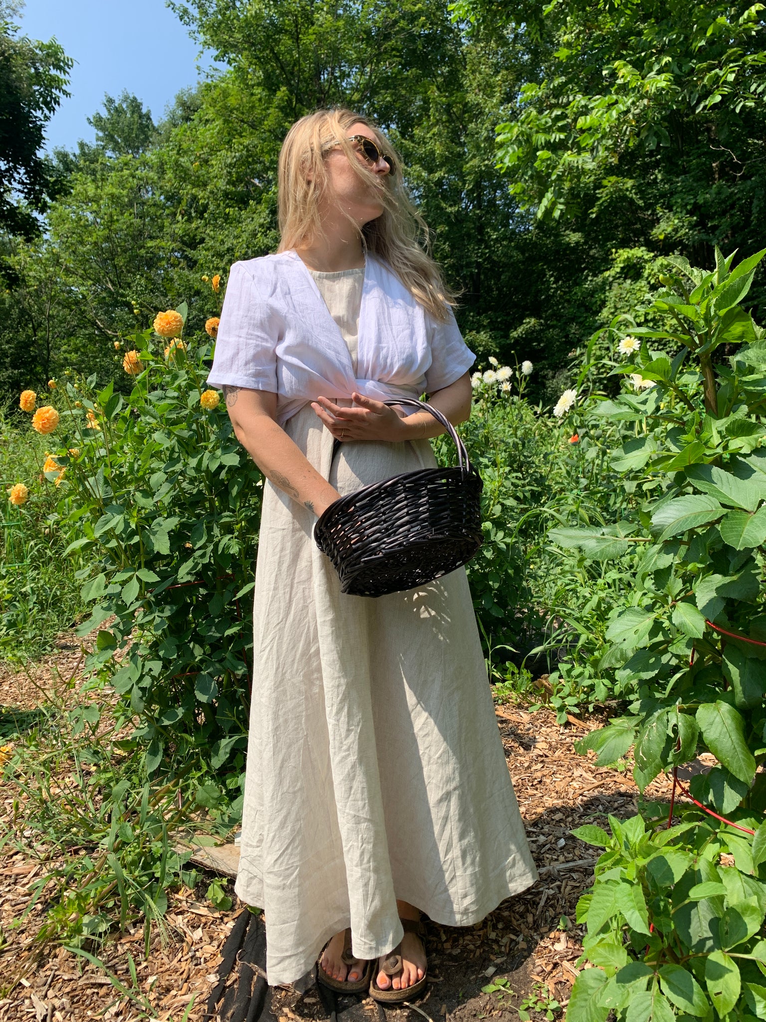 Woman wears beige maxi dress and white wrap top.