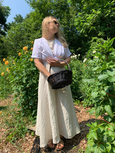 Woman wears beige maxi dress and white wrap top.