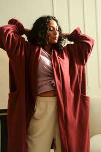 woman standing with her arms up wearing an oversized burgundy fleece cardigan