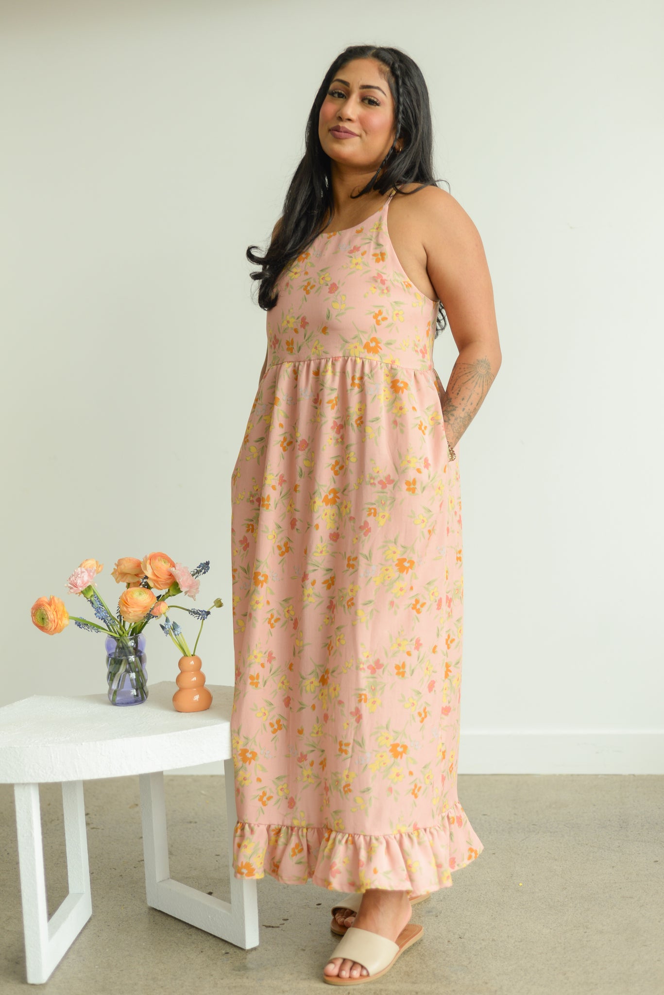 a female model wearing a soft pink floral maxi sleeveless dress 