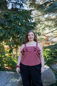 plus size model wearing a red tank top with ruffles and black loose pants in a park