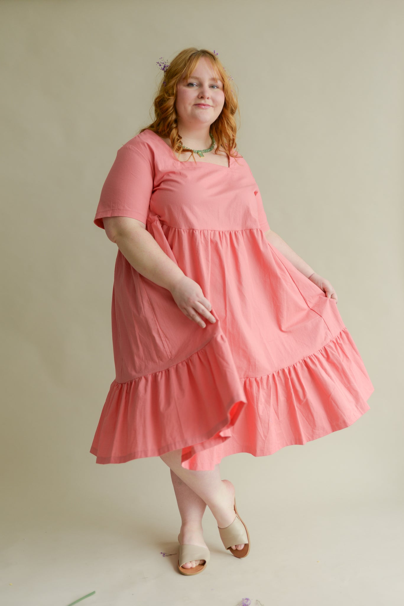 plus size model wearing a bright pink tiered midi dress with a square neckline