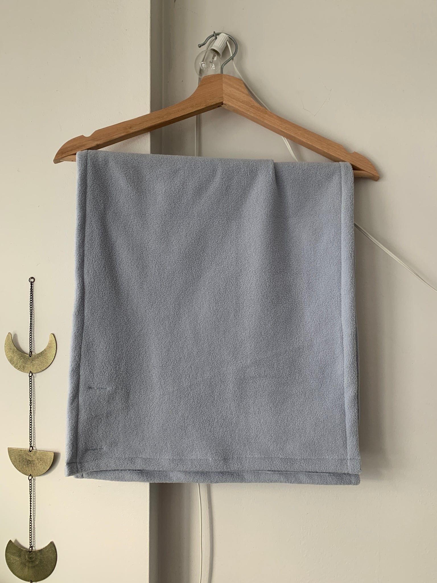 pale blue fleece scarf hanging folded on a hanger