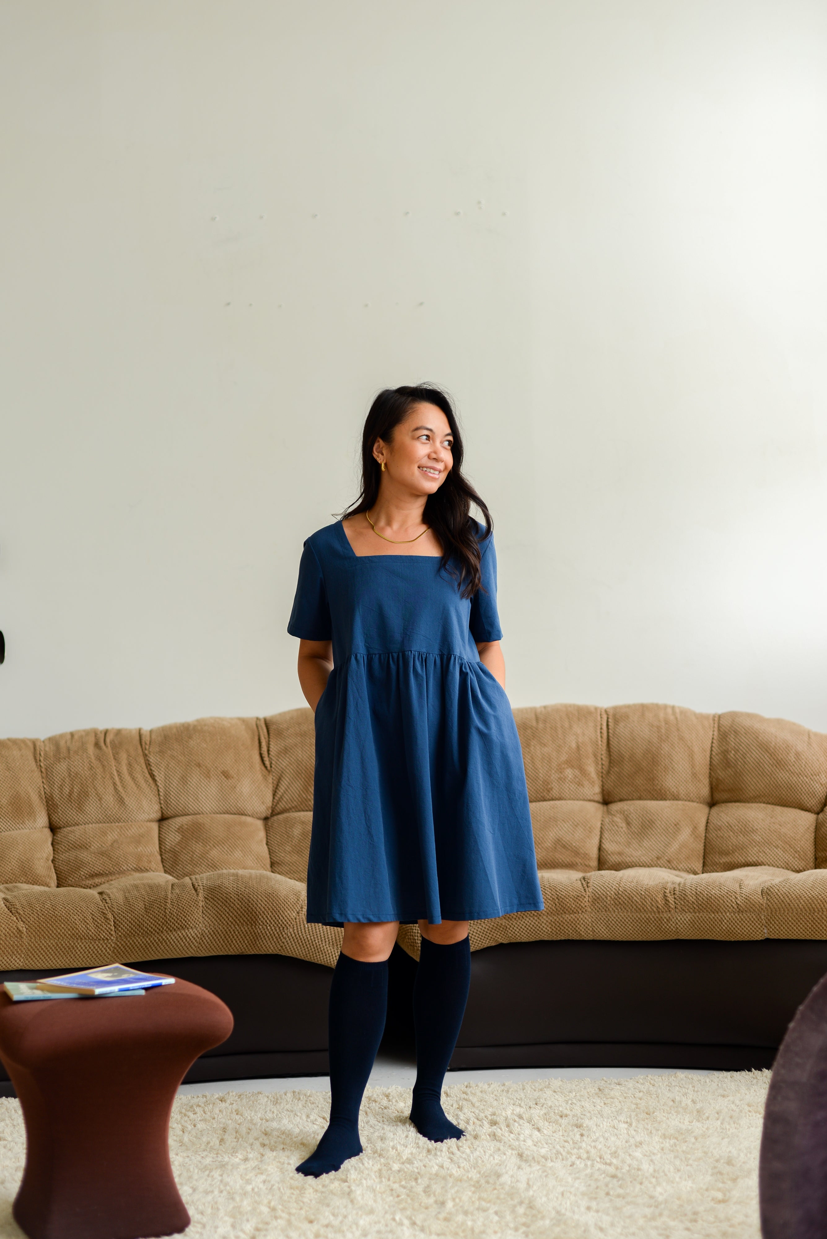 petite woman wearing a dark blue square neck mini dress with knee high socks