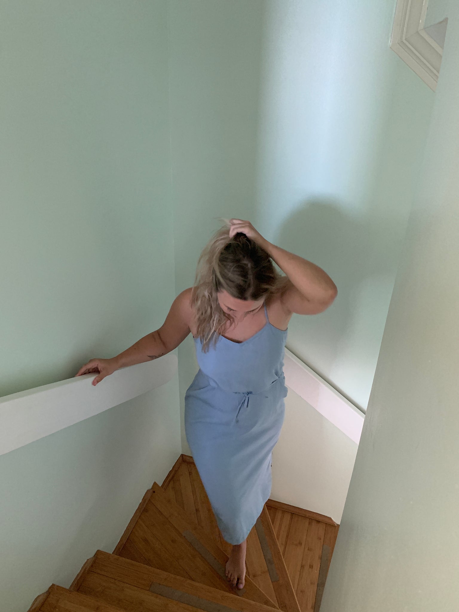 woman wearing a pale blue slip dress in a staircase
