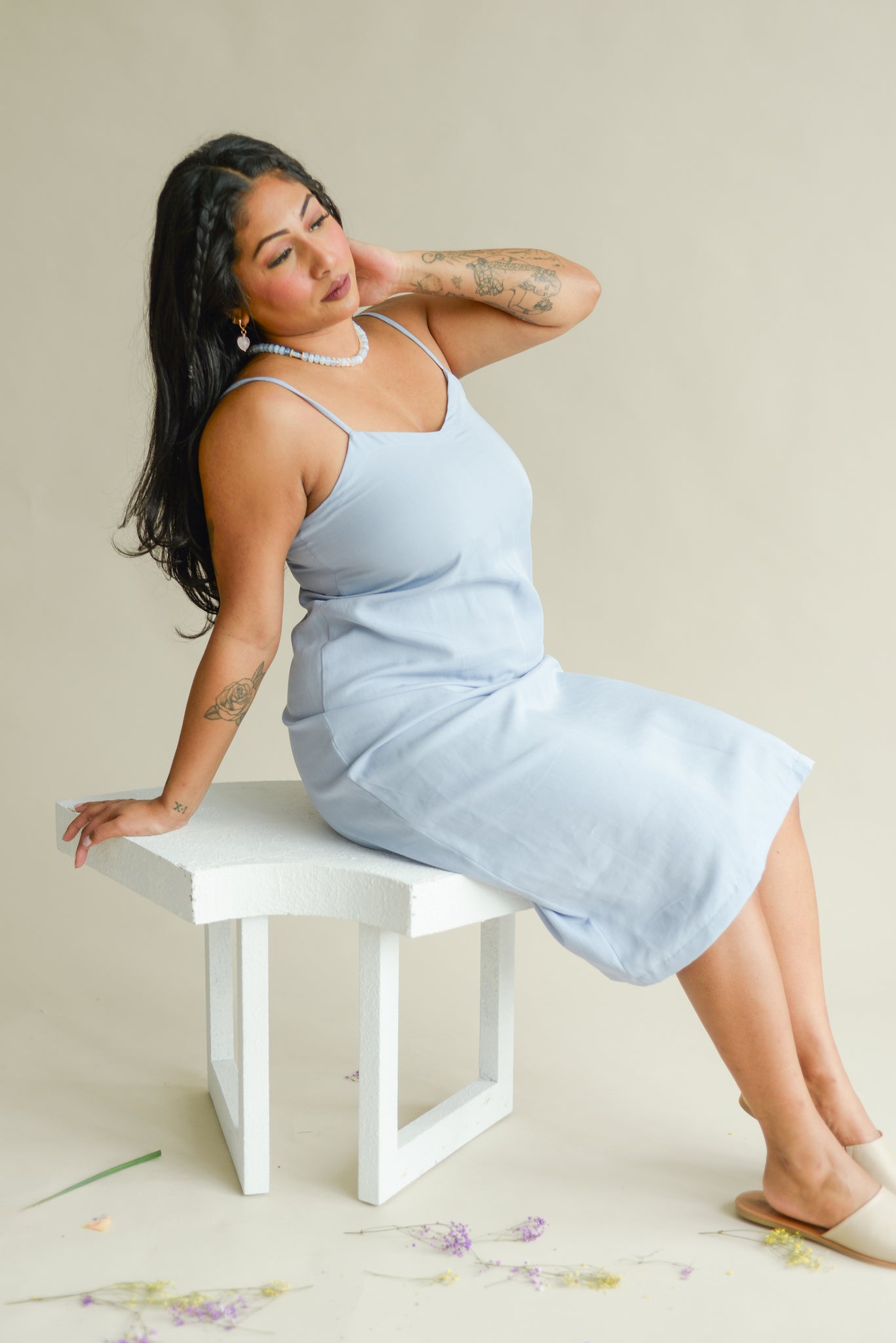 model sitting on a bench wearing a pale blue slip dress